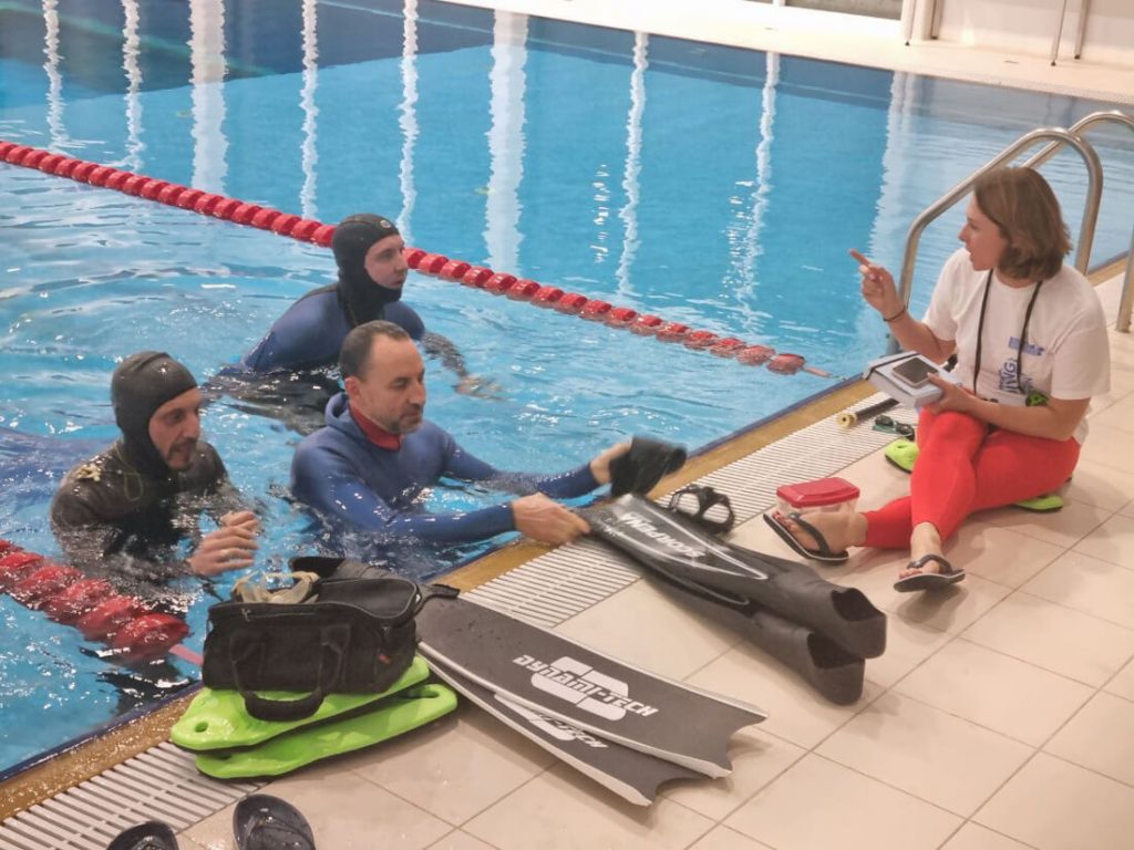 студенты в бассейне слушают инструктора